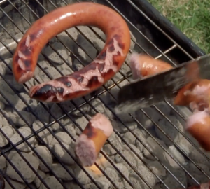 Des saucisses sur un barbecue et la lame d'un couteau