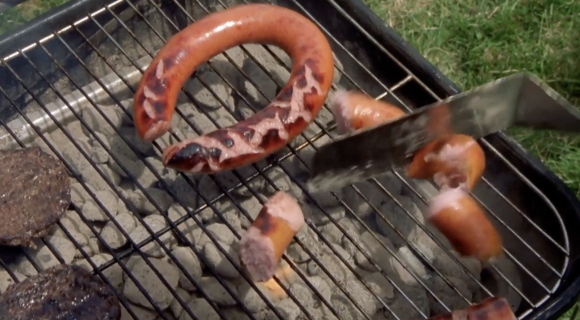 Des saucisses sur un barbecue et la lame d'un couteau