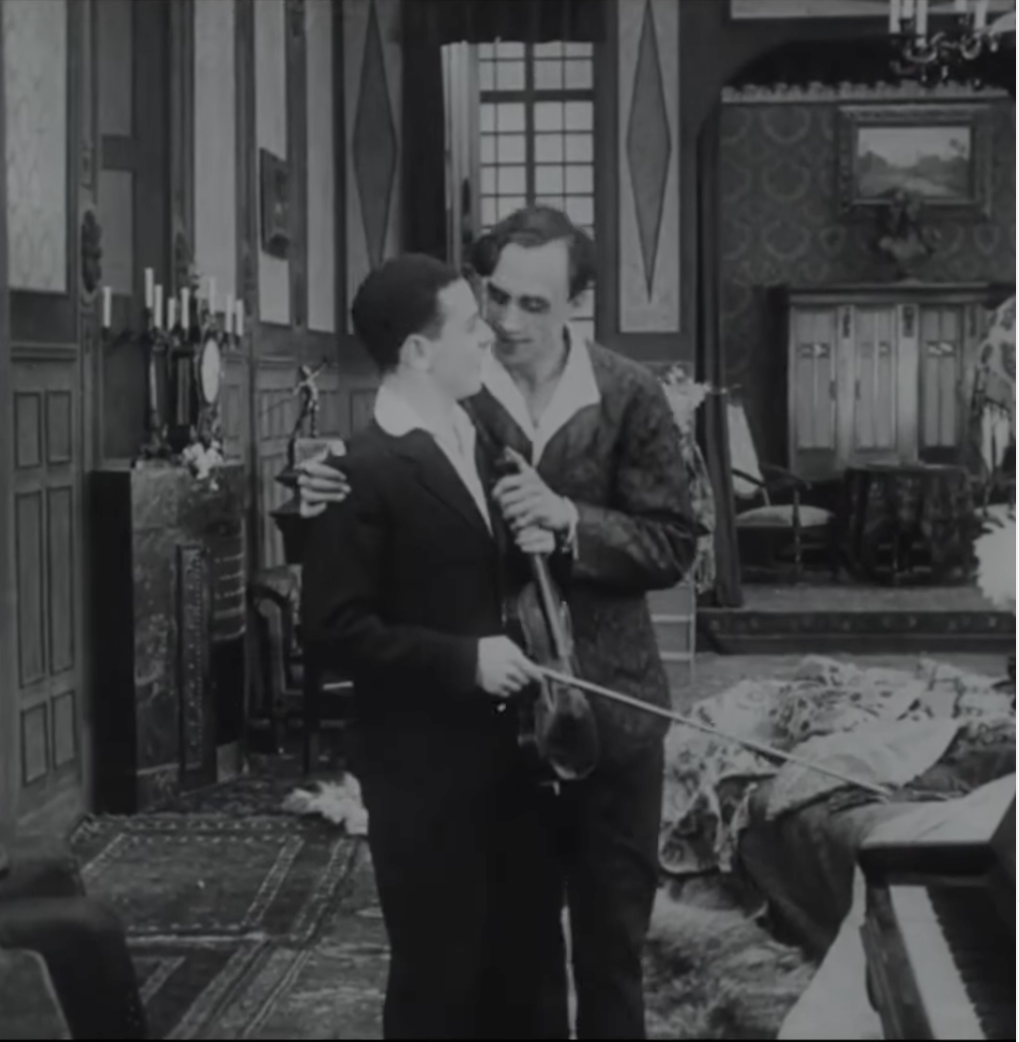 Image en noir et blanc. Un homme tient par l'épaule un jeune violoniste