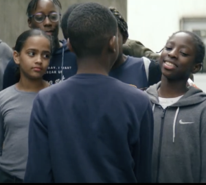 Un petit garçon face à des filles dans une cour de récréation