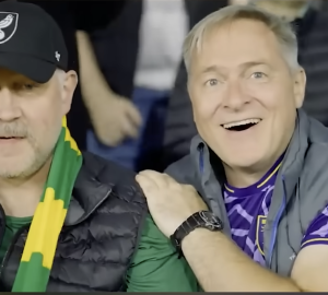 2 hommes pendant un match de foot, l'un joyeux, l'autre pas