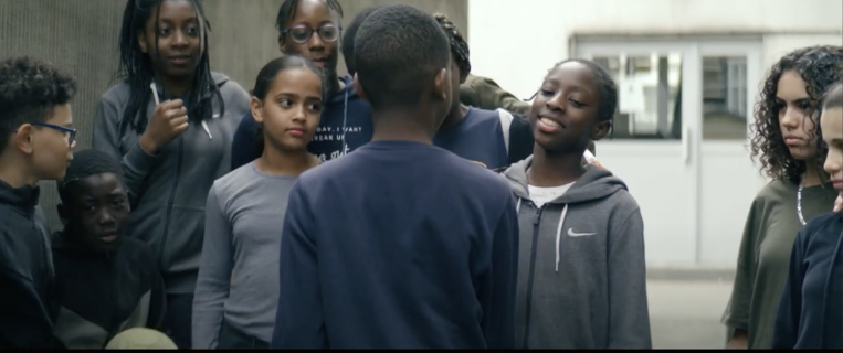 Un petit garçon face à des filles dans une cour de récréation